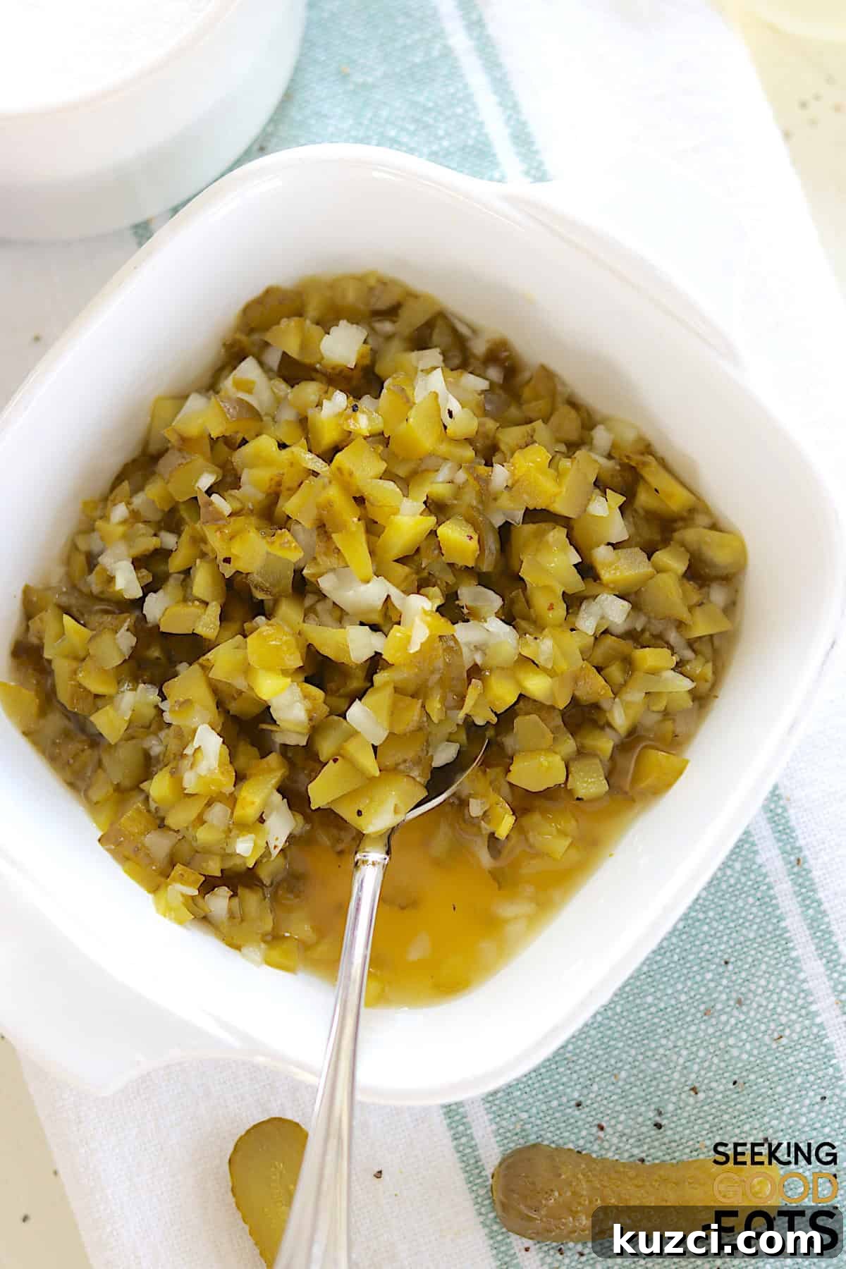 Homemade dill pickle relish served in a white square serving dish and a silver spoon.