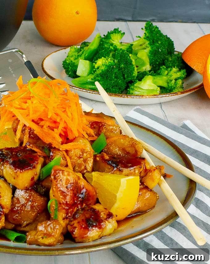 Sticky Orange Chicken Recipe with Tangy Citrus Glaze 7 plate of sticky orange chicken with broccoli in the background