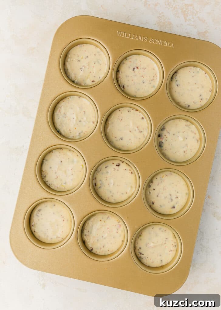 Mini Easter Egg Cheesecakes with Chocolate Ganache Recipe 11 A pan of raw mini egg cheesecakes on a white and beige counter.