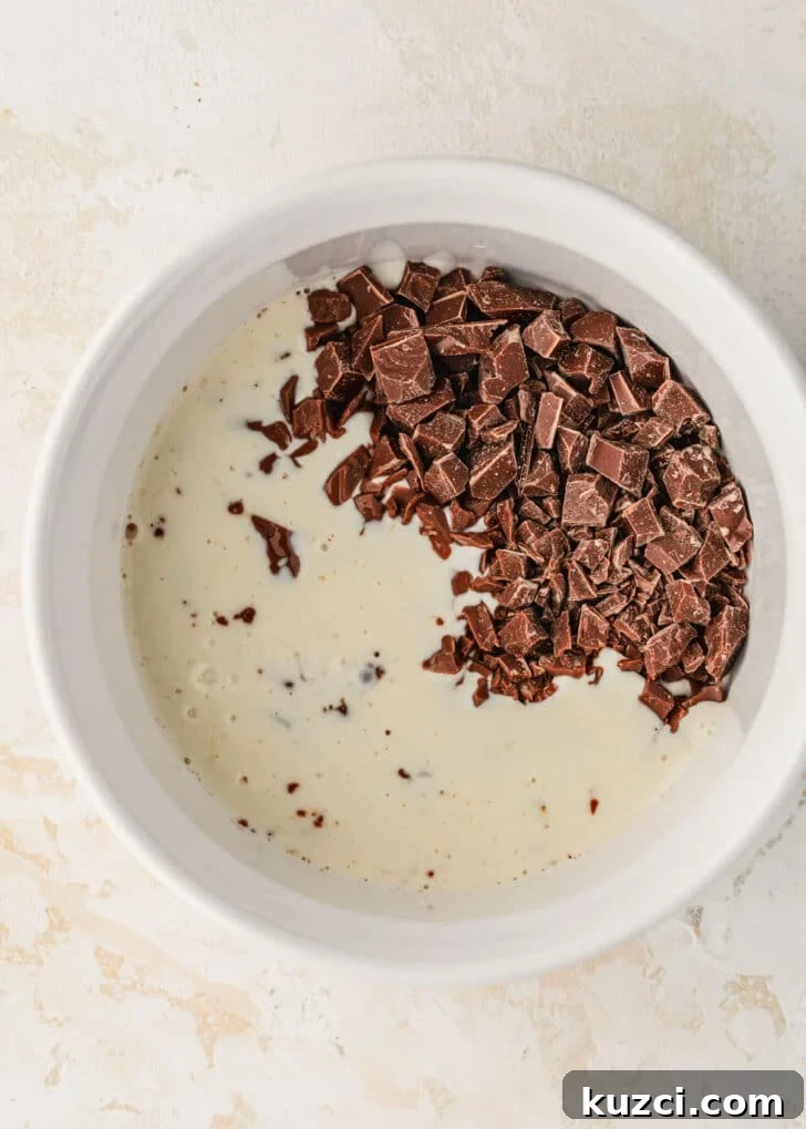 Mini Easter Egg Cheesecakes with Chocolate Ganache Recipe 14 A white bowl of chocolate and cream on a tan counter.