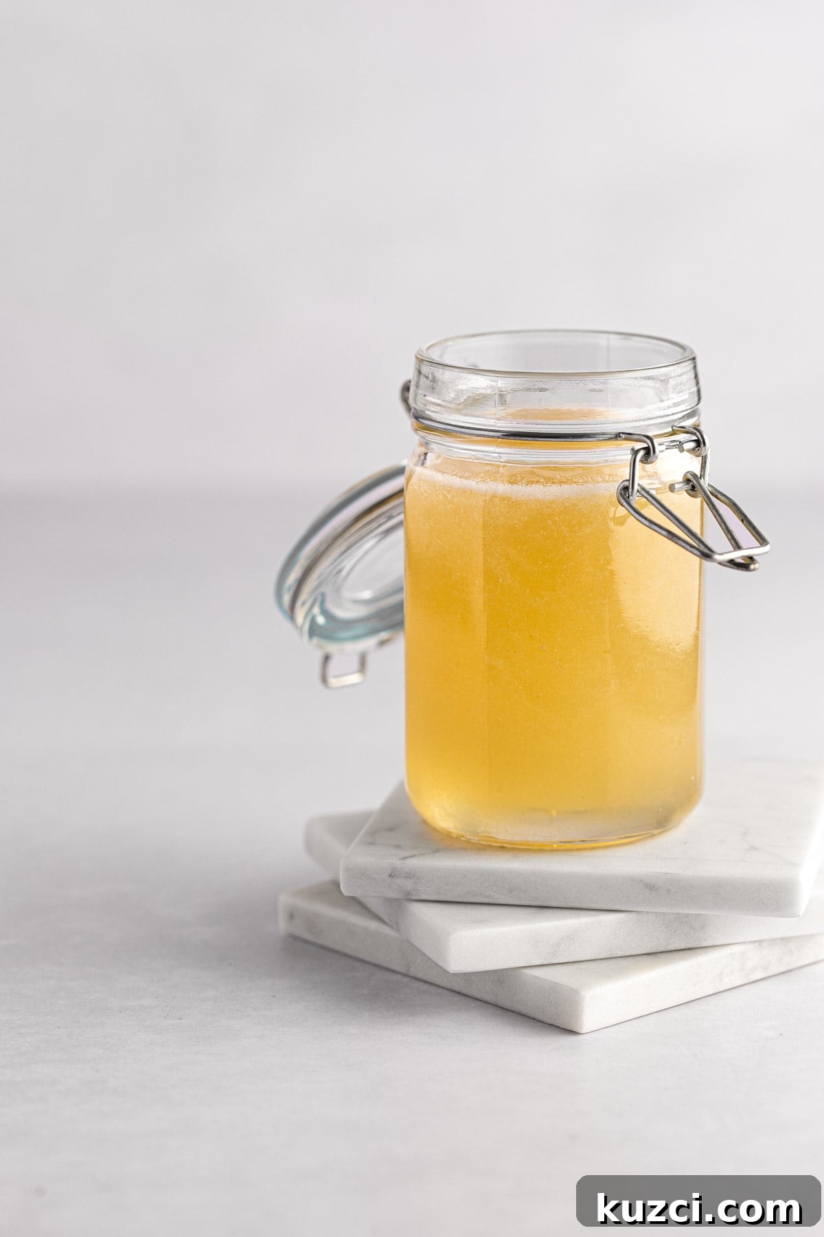 Homemade Banana Syrup for Pancakes, Cocktails and Desserts 2 A jar of banana syrup sitting on three square white marble coasters, on a white background.