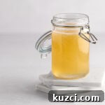 A jar of yellow banana syrup sitting on three white square marble coasters, on a white background.
