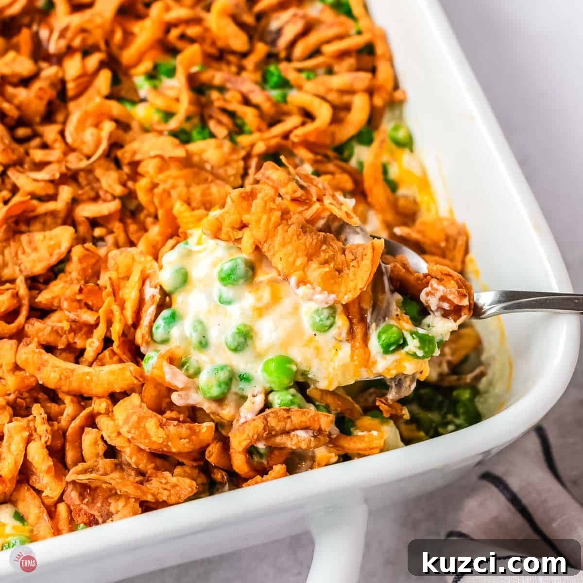 spoon scooping pea casserole out of a white dish