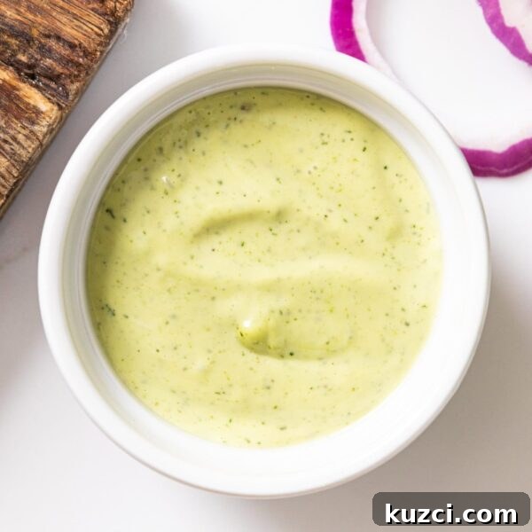 White bowl filled with dill aioli with a green color on white surface.