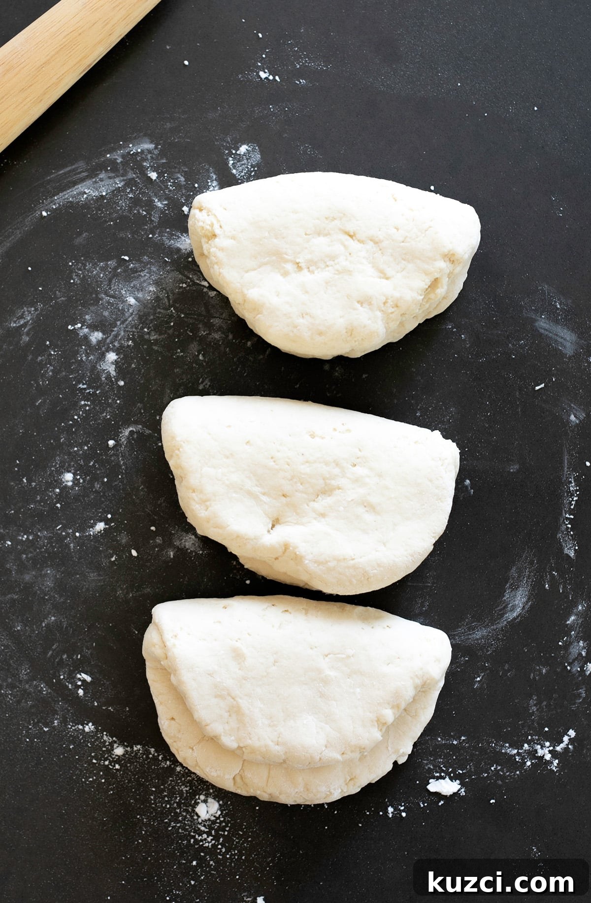 Three folded over pieces of raw bread dough on a board