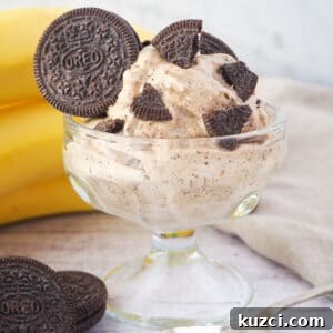 Cookies and Cream Nice Cream Recipe 14 Close up Serve of cookies and cream nice cream in a bowl, with pieces of Oreos, bananas and whole Oreos in the background.