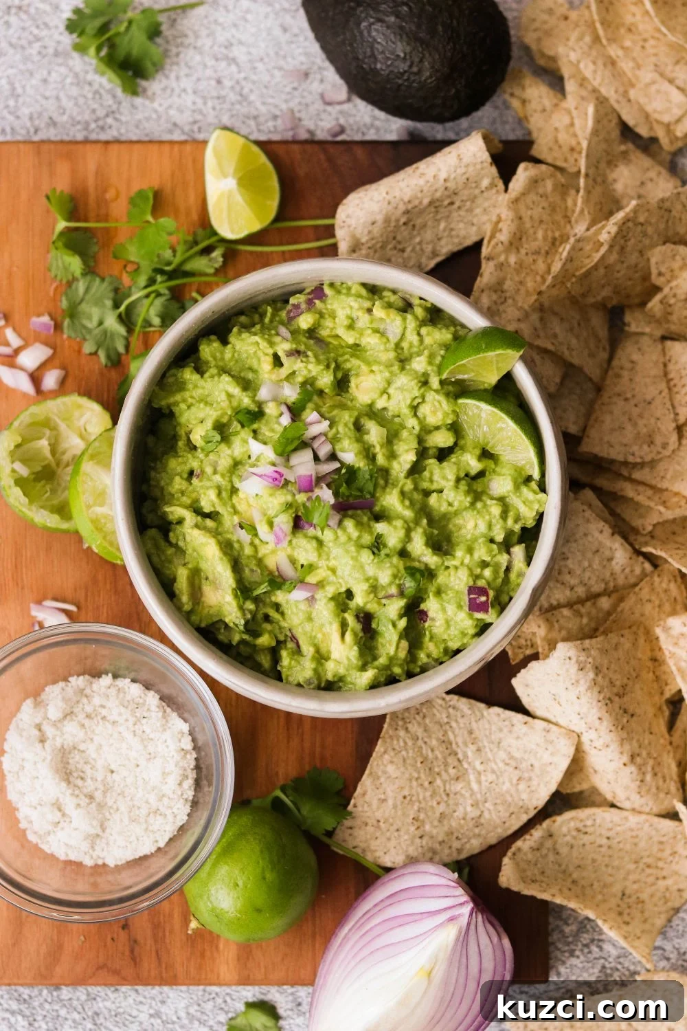 Homemade Keto Guacamole Recipe for Low Carb Avocado Dip 5 an overhead shot of avocado mashed in a bowl with lime wedges, onions, and cilantro