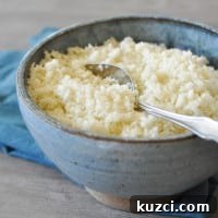 basic cauliflower rice in a blue bowl with a blue napkin on top of a grey wooden table