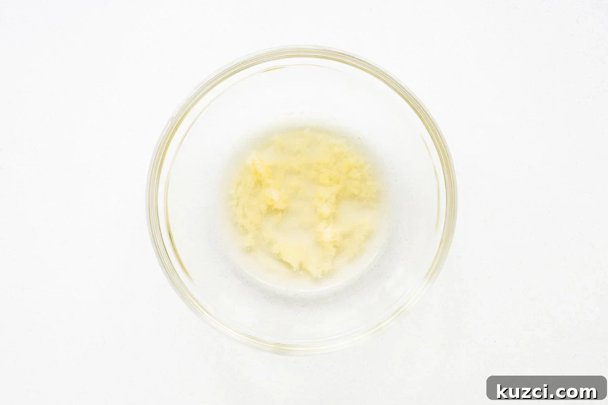 Grated garlic in a bowl with apple cider vinegar viewed from above.