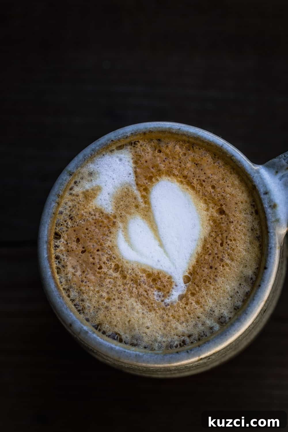 A cappuccino with a foam shaped heart in a ceramic cup.