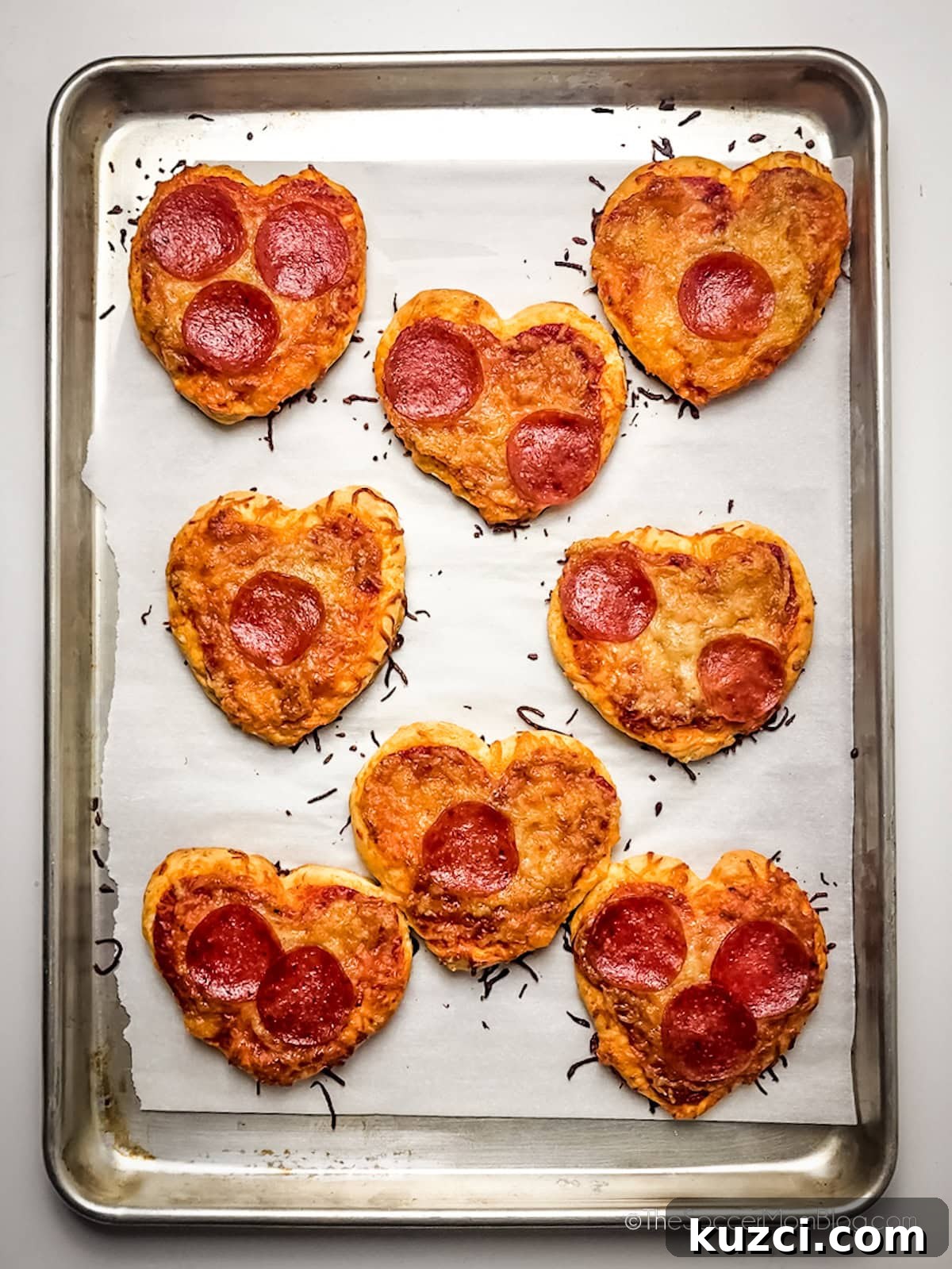mini heart shaped pizzas on a baking sheet.