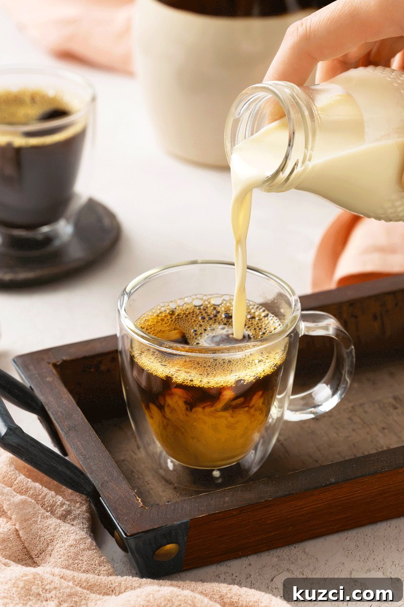 Homemade Vanilla Coffee Creamer Recipe 2 Homemade coffee creamer being poured from a glass bottle into a hot cup of coffee.