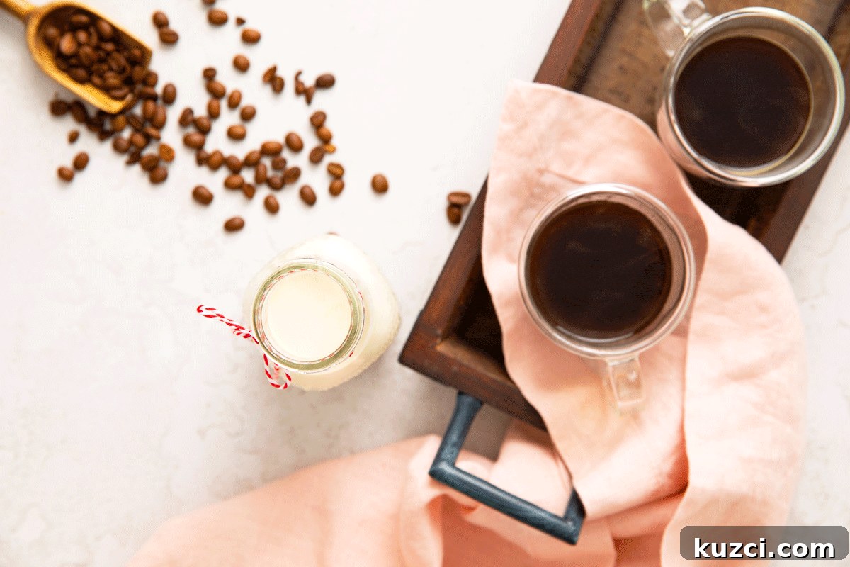 Homemade Vanilla Coffee Creamer Recipe 3 A glass bottle of homemade coffee creamer with a cup of hot coffee and coffee beans next to it.
