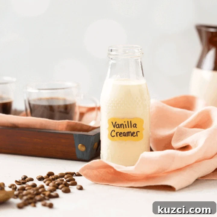 A glass bottle of homemade coffee creamer with a cup of hot coffee and coffee beans next to it.