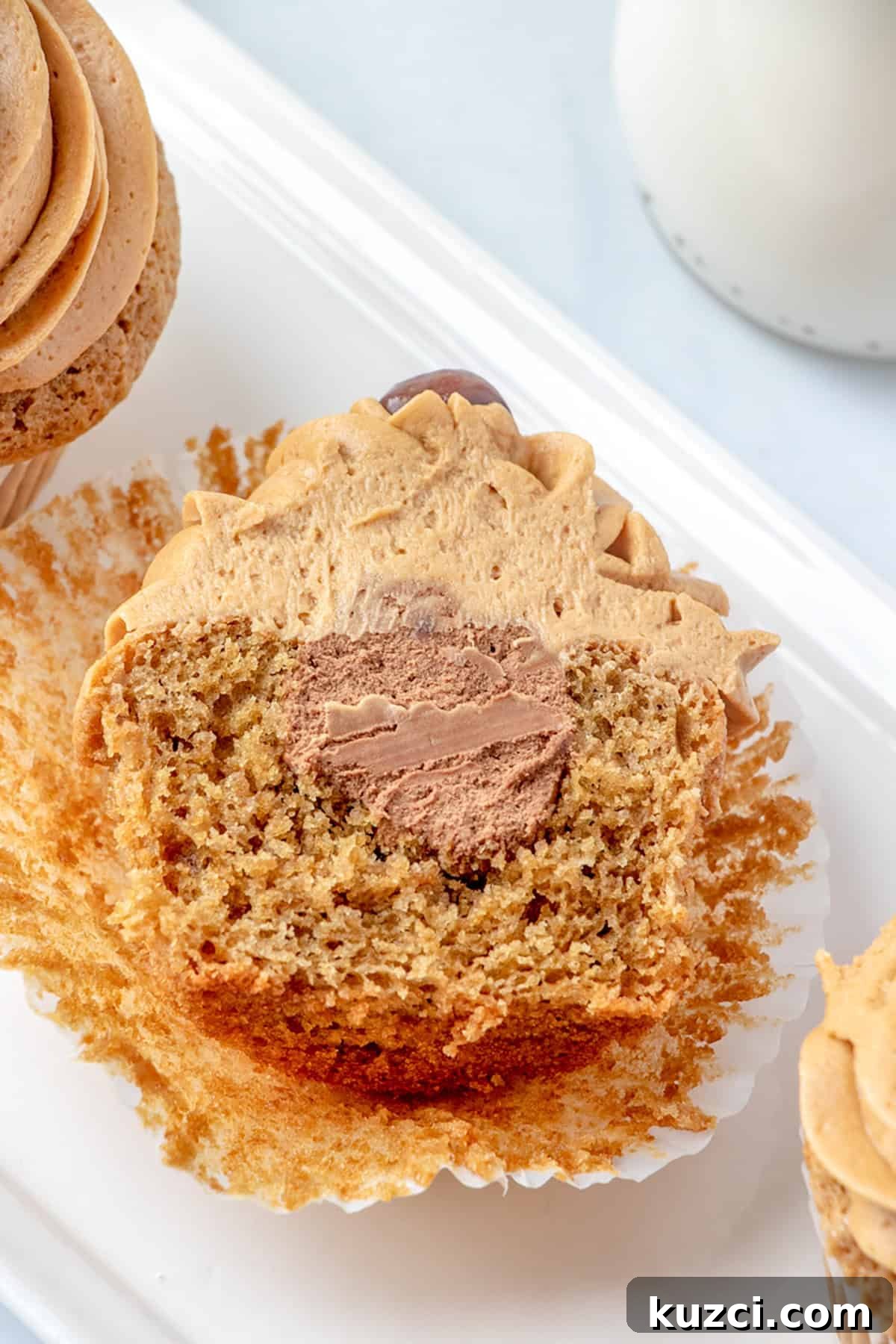 Coffee Cupcake Recipe with Coffee Buttercream Frosting 6 A sliced Coffee Cupcake with brown frosting reveals a chocolate cream filling inside.