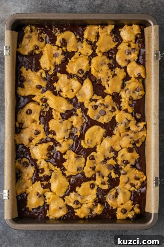 Drop spoonfuls of dough over the batter. Unbaked brookies in a parchment-lined baking pan.