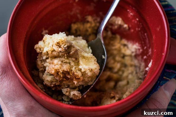 Microwave Coffee Cake in a Mug 4 Up close of coffee cake in a mug and a spoon inside.