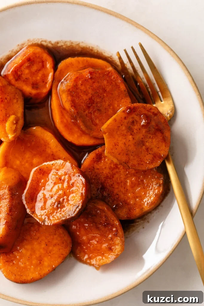 18 Soul Food Side Dishes to Elevate Your Thanksgiving 2 Candied Yams in a white bowl with gold trim and a gold fork.