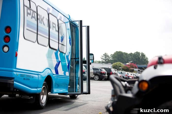 A blue Park n Fly Shuttle bus in a parking lot with its doors open.