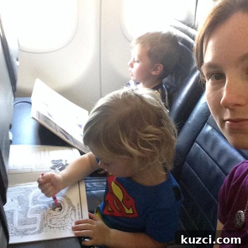 A woman seated in an airplane seat with two small children sitting next to her on an airplane.