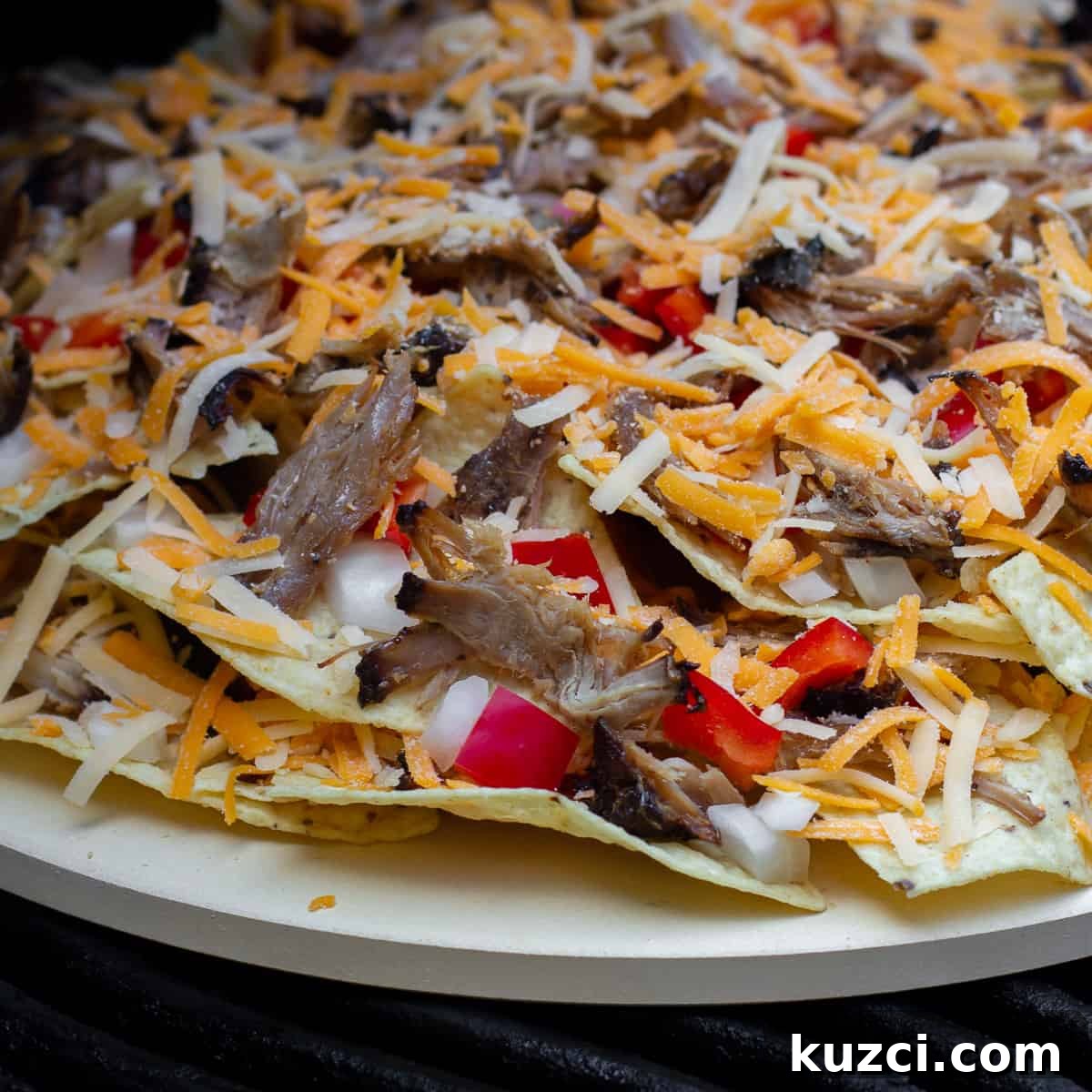 Pulled Pork Nachos with Melted Cheese and Jalapeños 3 A pizza stone with nachos piled on and ready to go on the grill or in the oven.
